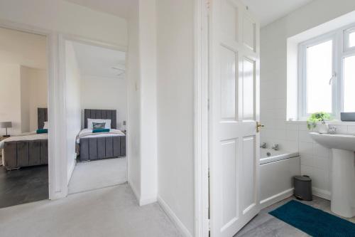 a white bathroom with a sink and a bed at Cheerful Chingford, Beautiful Views, Free Parking in Ponders End