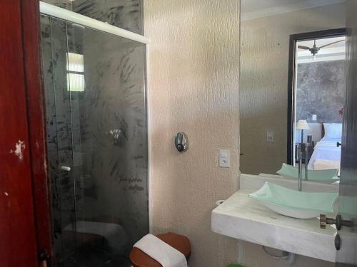 a bathroom with a glass shower and a sink at Pousada do Suiço in Saquarema