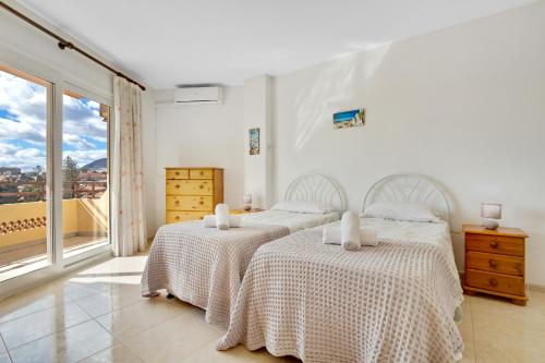 2 łóżka w białym pokoju z oknem w obiekcie Duquesa 506 by IVI Real Estate w mieście Torremolinos