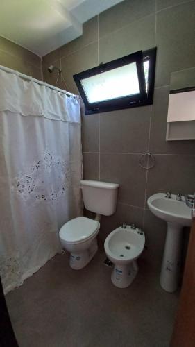 ein Bad mit einem WC, einem Waschbecken und einem Fenster in der Unterkunft Cubil Amarillo. Casa conteiner 1 dormitorio in General Roca