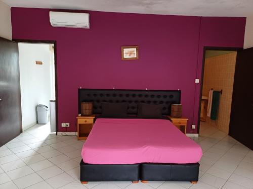 een slaapkamer met een roze bed in een paarse muur bij Le Palmier in Trou aux Biches
