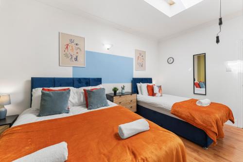 two beds in a white room with orange sheets at The Two-Bedroom Haven- Sleeps 10 in St. Albans