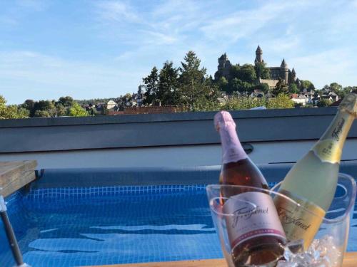 two bottles of wine in a glass next to a swimming pool at 4 Sterne Ferienwohnung Schlossblick Sauna Pool Whirlpool pri in Braunfels