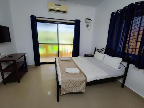 a bedroom with a bed and a large window at Maria Comfort Stay in Calangute