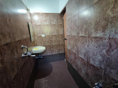 baño con lavabo y pared de piedra en Maria Comfort Stay, en Calangute
