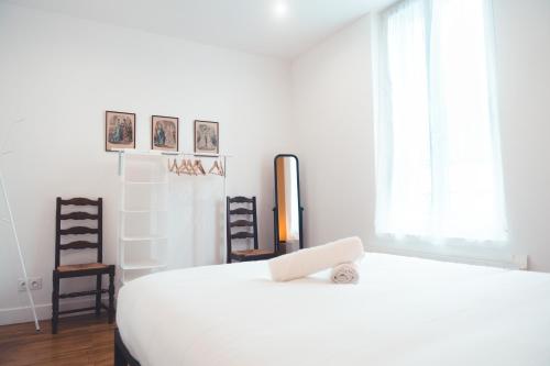 une chambre avec un lit blanc et deux chaises dans l'établissement Le Cabernet, T2 centre ville, à Tours
