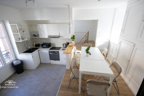 uma cozinha branca com uma mesa e cadeiras brancas em Le Refuge des Grands Rassemblements em Châteaudun