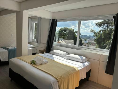 a bedroom with a bed and a large window at Hotel Golden Hills in Canela