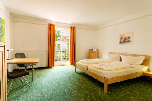 a bedroom with a bed and a desk and a deskablish at Hotel Bördehof in Barleben