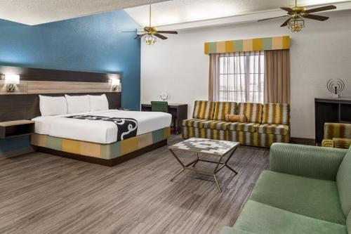 La Quinta Inn by Wyndham Victoria في فيكتوريا: غرفه فندقيه بسرير واريكه