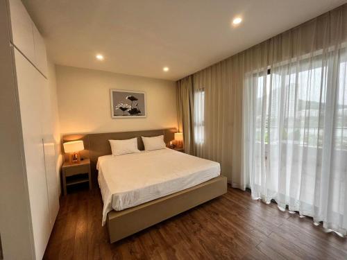 1 dormitorio con cama y ventana grande en Royal Lotus Hạ Long Resort - kiko resort, en Ha Long