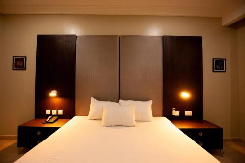 um quarto com uma cama grande com lençóis brancos e almofadas em Genesis Reventon Hotel em Port Harcourt