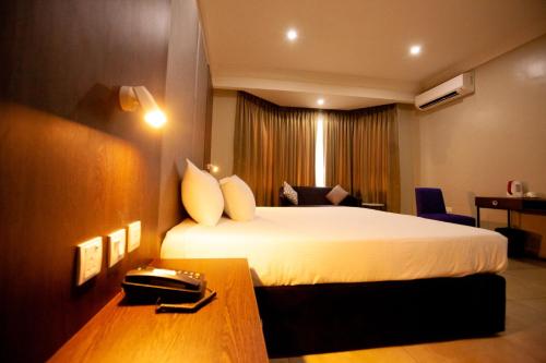 una habitación de hotel con una cama y un teléfono en un escritorio en Genesis Reventon Hotel, en Port Harcourt