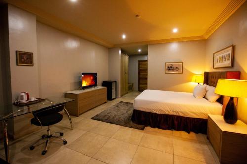 Habitación de hotel con cama, escritorio y TV. en Genesis Reventon Hotel, en Port Harcourt