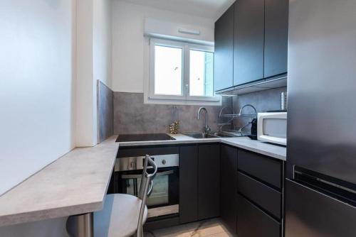 d'une cuisine avec des placards noirs, un évier et une fenêtre. dans l'établissement LOUIS GALLET Centre JUAN LES PINS 50m des plages, à Antibes