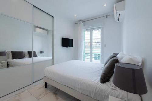 Habitación blanca con cama y espejo en CENTER JUAN LES PINS 50 M DES PLAGES, en Antibes
