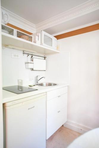 a white kitchen with a sink and a microwave at Villa Escudier Appart-hôtel in Boulogne-Billancourt