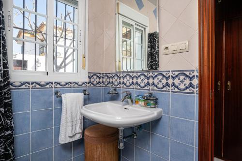 a blue tiled bathroom with a sink and a mirror at Chalet Estribor in Chiclana de la Frontera