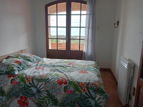 - une chambre avec un lit avec une couette à fleurs et une fenêtre dans l'établissement Les Asphodèles, à Sausset-les-Pins