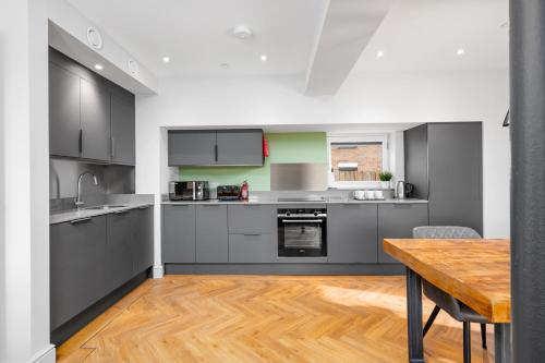 鄧弗姆林的住宿－312 Reids Corner - by StayDunfermline，厨房配有灰色的橱柜和木桌。