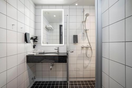 a bathroom with a sink and a shower with a mirror at Thon Hotel Tromsø in Tromsø