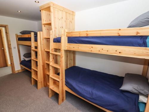 two bunk beds in a room with blue sheets at Dales Lodge in Ingleton