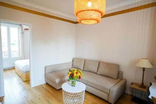 a living room with a couch and a table with flowers on it at Villa Escudier Appart-hôtel in Boulogne-Billancourt