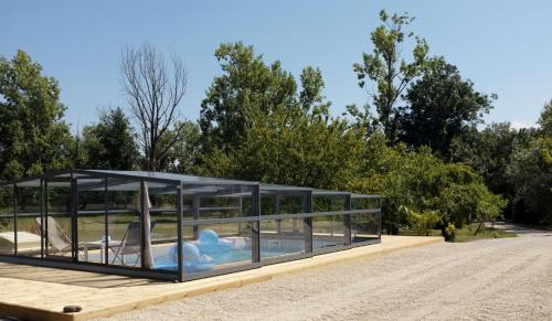 une maison en verre avec une piscine dans un parc dans l'établissement Chateau Haut Baron, à Saint-Estèphe