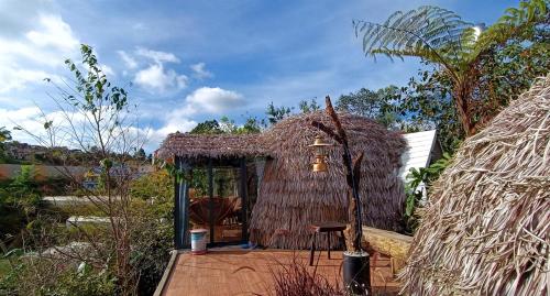 Cabaña pequeña con techo de paja y mesa en Nature Homes Đà Lạt en Da Lat