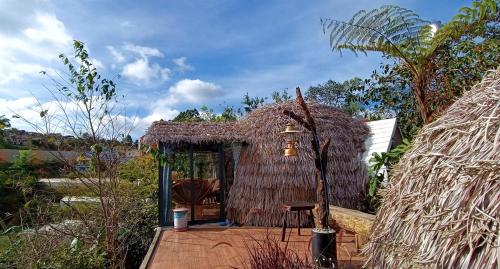 una piccola capanna con tetto di paglia e tavolo di Natural Home Đà Lạt a Da Lat