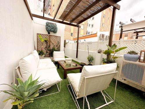 een patio met witte stoelen, een tafel en planten bij Ático Duplex Triana , Sevilla in Sevilla