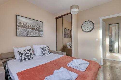 une chambre avec un lit et une horloge au mur dans l'établissement Ideal & Comfy Cocoon at the Luxury Paris 16., à Paris