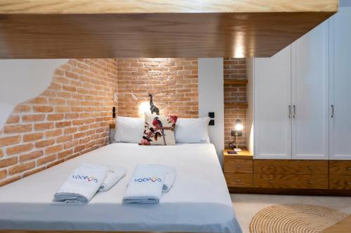 a bedroom with a white bed with a brick wall at Dirapera Port Suite in Corfu Town