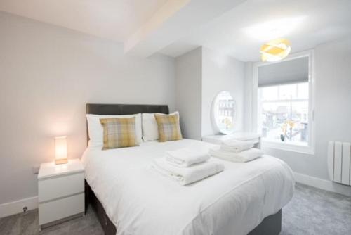 a white bedroom with a large bed and a window at Modern,central 1 bedroom flat in Brentwood