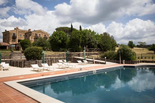 a swimming pool with chairs and a house in the background at Tenuta Fattoria Vecchia in Scansano