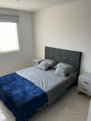 Un dormitorio con una cama con una manta azul y una ventana. en Apartamento en San gil, en San Gil