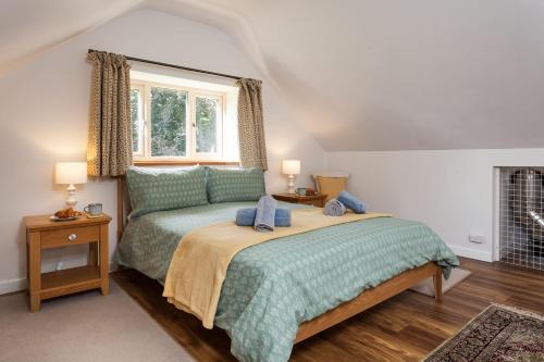 a bedroom with a bed with a green comforter and a window at The Sunset Retreat in Banbury