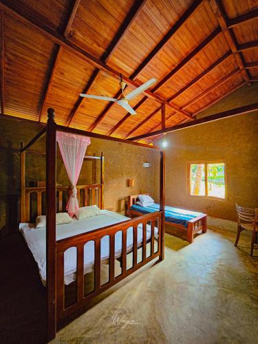a bedroom with two beds and a ceiling fan at River Edge Safari Cottage in Udawalawe