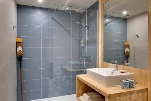 a bathroom with a sink and a shower at Hôtel Île de Lumière in La Cotinière