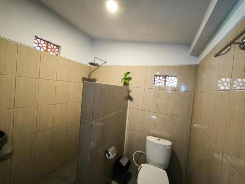 a bathroom with a toilet and a plant on the wall at Eling Ubud Guesthouse in Ubud