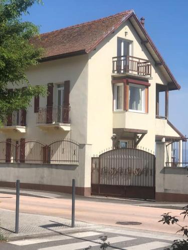 a large white house with a gate and balcony at Villa Les Sources - Les pieds dans l'eau in Lugrin