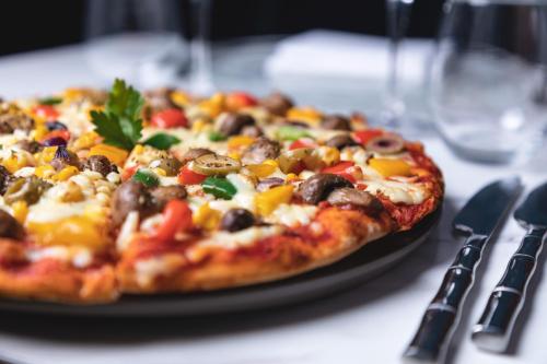 uma pizza sentada num prato numa mesa em The George Hotel Pangbourne em Pangbourne