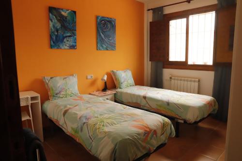 two beds in a room with orange walls at Villa Soluna in Cantoria