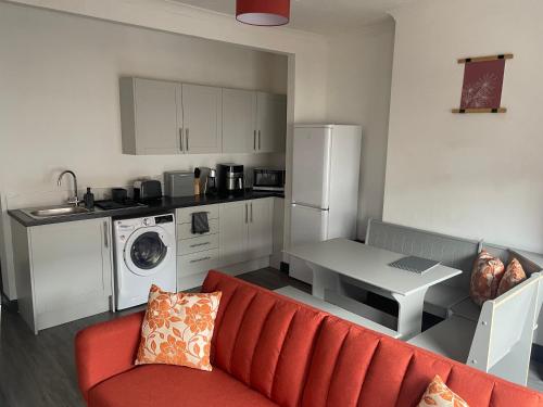 a living room with a red couch and a kitchen at Quirky and Cosy Self Contained Flat, Ferryhill Near Durham in Ferryhill