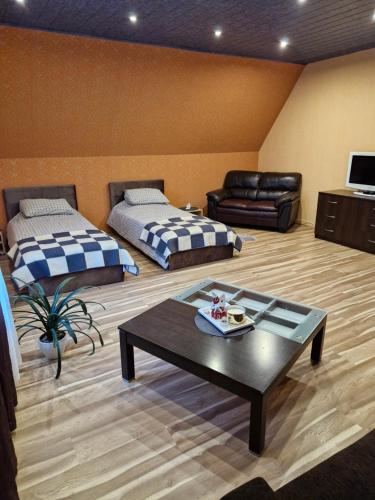 a living room with two beds and a coffee table at Inkiliuko apartamentai Ketvergiuose in Kalviai