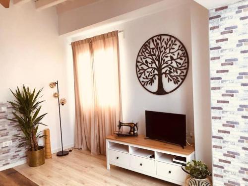 ein Wohnzimmer mit einem TV und einem Baum an der Wand in der Unterkunft Disfruta, nuevo en Mentidero in Cádiz