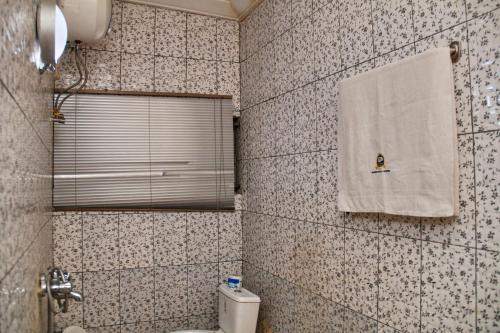 een badkamer met een toilet en een handdoek aan de muur bij GLAMOUR PARK'S HOTEL, ABUJA in Abuja