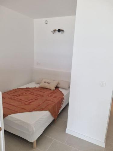 une chambre avec un lit dans une pièce blanche dans l'établissement Sur la plage avec vue plongeante sur la mer, à Marseillan