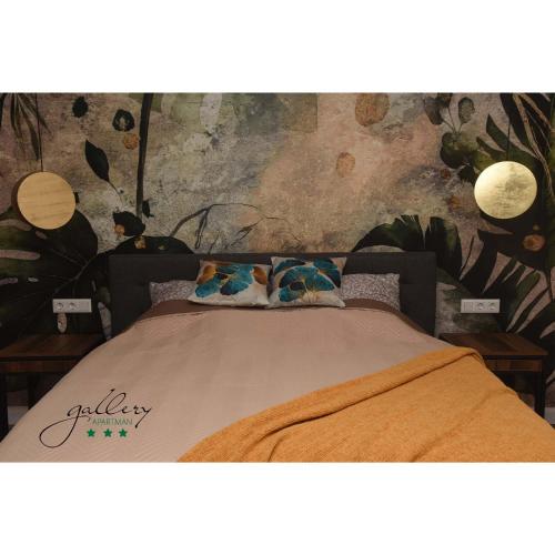 a bed in a bedroom with a wall with plants at Gallery Apartman in Győr