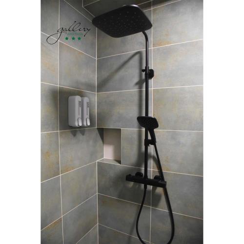 a shower with a shower head in a bathroom at Gallery Apartman in Győr